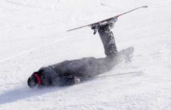 man falling on cold snow in ski crash